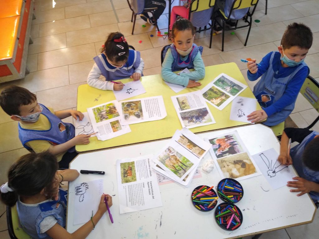 Niñas y niños elaborando el folleto sobre la mesa